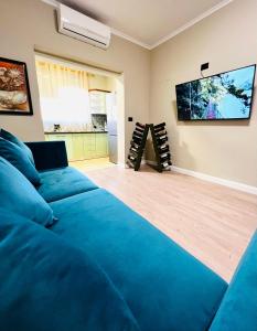 uma sala de estar com um sofá azul e uma televisão de ecrã plano em Bejart Apartment 3 em Tirana
