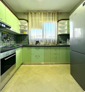a kitchen with green cabinets and a refrigerator at Bejart Apartment 3 in Tirana