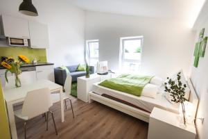 a small white room with a bed and a kitchen at Studios + in Graz