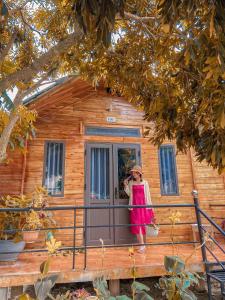 a woman standing on the front porch of a log cabin at Homestay 368 in Chung Cap