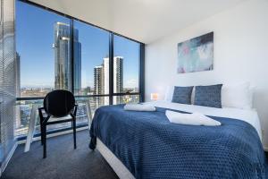 sypialnia z łóżkiem i krzesłem oraz dużymi oknami w obiekcie Mega Style Apartments Mainpoint w Melbourne