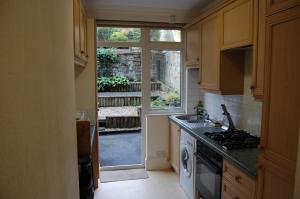 cocina con fregadero, fogones y ventana en Central Regent Terrace Apartment, en Edimburgo
