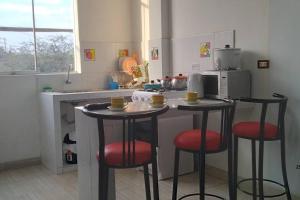 a kitchen with two bar stools and a microwave at Departamento - Los Mitos del Parque M2 in Chiclayo