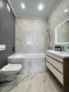 uma casa de banho com uma banheira, um WC e um lavatório. em Современная квартира в новом доме em Pavlodar