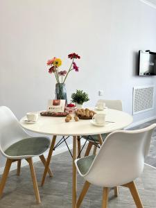 uma mesa branca com cadeiras e um vaso com flores em Современная квартира в новом доме em Pavlodar