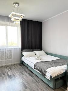 um quarto com uma cama grande e um lustre em Современная квартира в новом доме em Pavlodar