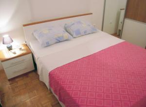 a bedroom with a large bed with a pink and white blanket at Family friendly house with a swimming pool Jezera, Murter - 5124 in Jezera