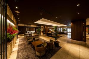 eine Lobby mit Stühlen und Tischen in einem Gebäude in der Unterkunft Kusatsu Estopia Hotel in Kusatsu