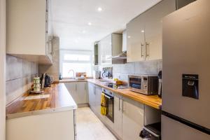 a kitchen with white cabinets and stainless steel appliances at Stunning 4 bedroom house with Garden, Parking & 3 mins Walking Distance from Train Station in London