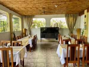 Lapu-Lapu Cottages & Restaurant في ماكتان: مطعم بطاولات وكراسي وتلفزيون بشاشة مسطحة