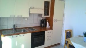 una cocina con armarios blancos y fregadero en Apartment Jezera 5057g, en Jezera