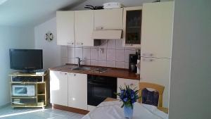 a small kitchen with white cabinets and a television at Apartment Jezera 5057g in Jezera