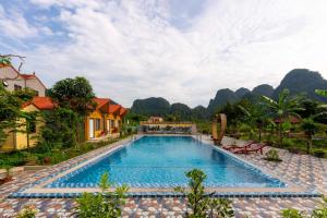 a swimming pool in a resort with mountains in the background at Tan Dinh Farmstay in Ninh Binh