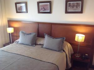 a bedroom with a bed with two pillows and two lamps at Olas Apart High Comfort in Villa Gesell