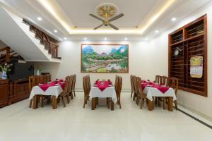 a dining room with tables and chairs and a painting at Tan Dinh Farmstay in Ninh Binh