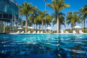 una piscina con palme e sedie di Oscar Inn Eco Resort ad Águas de Lindóia