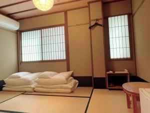 a room with a bed with white sheets and windows at Roman Kan in Kyoto