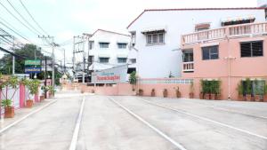 une rue vide avec des bâtiments roses et blancs dans l'établissement Visanuinn Hotel, à Nakhon Sawan