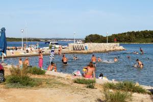 a group of people in the water at a beach at Secluded holiday house Pasman - 15649 in Pašman +14 photos