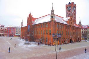 duży budynek z czerwonej cegły z wieżą zegarową w obiekcie Angel Hostel w Toruniu