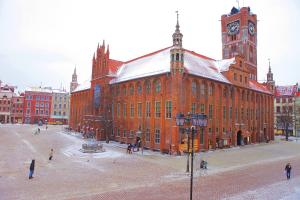 un gran edificio de ladrillo rojo con una torre de reloj en Angel Hostel, en Toruń