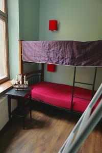 a bedroom with a bunk bed with a red bedspread at Angel Hostel in Toruń