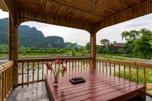 a wooden porch with a table with flowers on it at Tan Dinh Farmstay in Ninh Binh