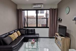 uma sala de estar com um sofá de couro preto e uma televisão em 8FINITE House em Bang Su