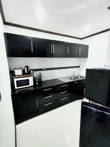 a kitchen with black cabinets and a microwave at Patong Tower Amazing Sea View 12 by PHR in Patong Beach