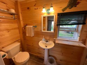 baño con lavabo y aseo y ventana en The Coastal Cabins in New Brunswick, en Cape Tormentine