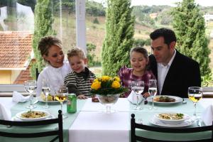 a family sitting at a table in a restaurant at Hotel Villa Michelon in Bento Gonçalves
