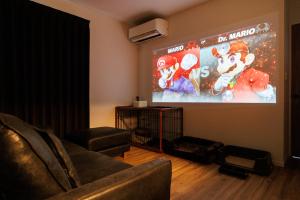 ein Wohnzimmer mit einem großen Bildschirm mit einem Videospiel in der Unterkunft しっぽの森リゾート淡路島〜サウナ&スタジオ〜 in Awaji