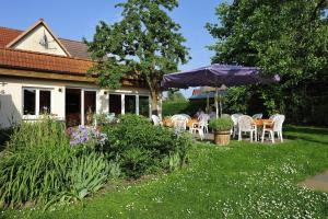 einen Garten mit Tischen, Stühlen und einem Sonnenschirm in der Unterkunft Gasthaus Zum Rethberg in Lübstorf