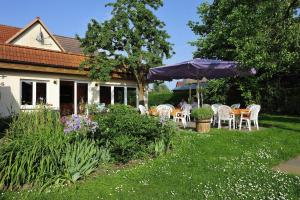 un jardín con mesas, sillas y una sombrilla en Gasthaus Zum Rethberg, en Lübstorf