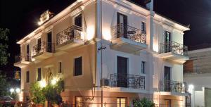 - un grand bâtiment blanc avec balcon et éclairage dans l'établissement Villa Ianthia, à Galaxidi
