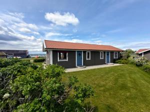 een klein huis met een rood dak en een tuin bij Talluddens Stugby in Färjestaden