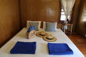 a bed with two hats and a basket on it at The Mermaid House in Ko Kood