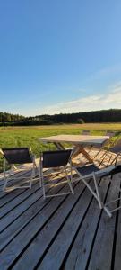a table and two chairs on a wooden deck at Domek drewniany letniskowy całoroczny nad jeziorem in Grądy