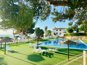a pool with chairs and umbrellas next to the ocean at La Suite Del Mar in Gran Alacant