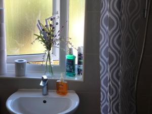 a bathroom sink with a vase of flowers in a window at Cosy relaxing 4 bed Home with 2 parking Space in Hatch End