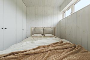 a bedroom with a bed with a blanket on it at Svencelės burė 8 in Svenele