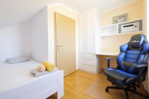 a bedroom with a bed and a blue chair at ITSOFT smart apartment in Komenda