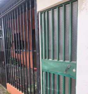 zielone drzwi z kratami na budynku w obiekcie Pinky’s Place Airport, Full Equipment. w mieście Alajuela