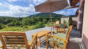 eine Terrasse mit einem Tisch, Stühlen und einem Sonnenschirm in der Unterkunft Blu Raj - domy w Sudetach in Głuszyca