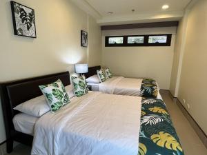 2 camas en una habitación con 2 ventanas en Anvaya Cove Short Term Rental Condos en Morong