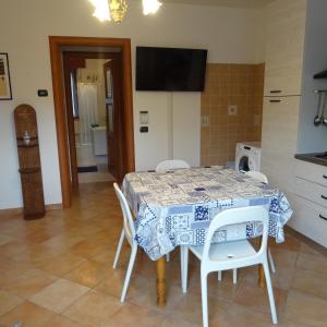 a kitchen with a table and white chairs in a room at Appartamento BLU - Colori del Lago D'Orta - NUOVA STRUTTURA A OMEGNA in Omegna