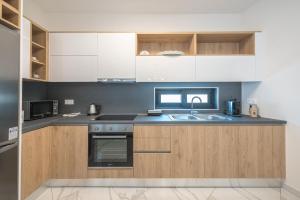 una cocina con armarios de madera y fregadero en Newly renovated apt in the heart of Kerameikos, en Atenas