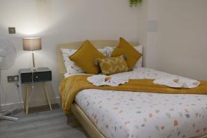 a bedroom with a bed with yellow pillows at MK SHORTSTAY DELUXE-Flat 2 in Milton Keynes