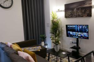 a living room with a couch and a flat screen tv at MK SHORTSTAY DELUXE-Flat 2 in Milton Keynes