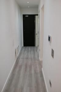 a hallway with a black door and a wooden floor at MK SHORTSTAY DELUXE-Flat 2 in Milton Keynes